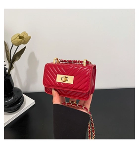Detail of red quilted lipstick bag with gold chain strap and metallic twist lock