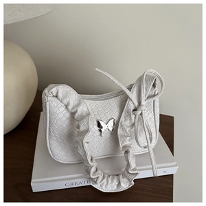 Détail du sac à texture tressée blanche avec papillon en métal et poignée plissée