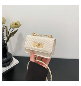 Detail of cream quilted mini lipstick bag with gold metal clasp and chain strap