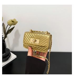 Detail of a mini gold quilted crossbody bag with chevron pattern and chain strap