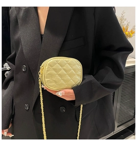 Detail of light yellow quilted mini crossbody bag with golden chain on black blazer