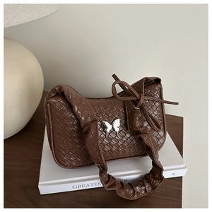 Détail du sac à main marron foncé tressé avec boucle papillon argentée et bandoulière plissée