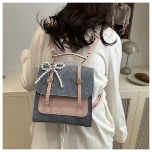 Détail d'un sac à dos gris et rose avec un grand nœud en perles porté par un mannequin