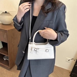 Minimalist white leather handbag with bow detail and adjustable shoulder strap shown on model
