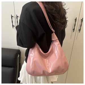 Detail of pink glossy patent leather hobo bag with a sleek finish and thin shoulder strap