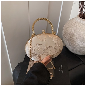Dettaglio di pochette in raso champagne con trama floreale e chiusura in cristallo
