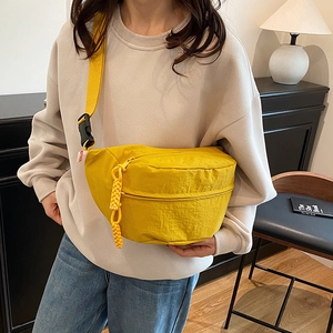 Minimalist bright yellow nylon crossbody bag featuring textured fabric and adjustable strap