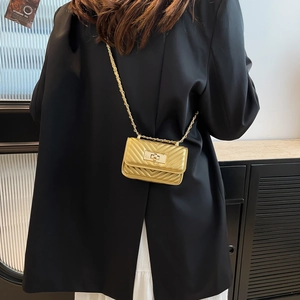 Mini gold crossbody bag with V-shaped quilting and chain strap worn by a model in black