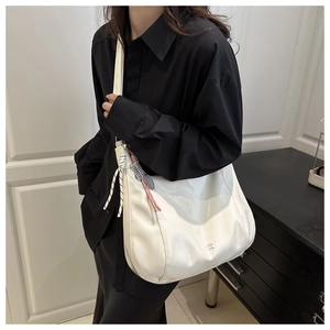 Detailed shot of white glossy leather tote bag with woven knot and pink metal tassel charm
