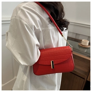 Detail of red croc-embossed leather shoulder bag with gold metal clasp and chain strap