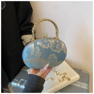 Dettaglio borsa da sera in seta azzurra con jacquard floreale dorato e chiusura in strass