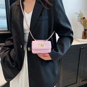 Pink quilted leather mini crossbody bag with gold chain strap on a model in a black blazer