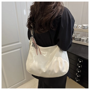 Detail of cream patent leather hobo bag with glossy finish and decorative floral ribbon