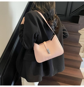 Detail of pink faux leather underarm bag featuring diagonal embossed texture and silver lock