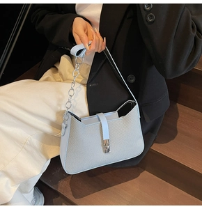 Detailed close-up of light blue shoulder bag featuring textured grey fabric and silver clasp