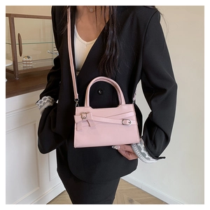 Detail of pink mini handbag with decorative bow and metal buckle on black blazer
