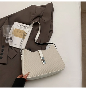 Detail showing cream woven texture with silver metal buckle and chain on underarm bag
