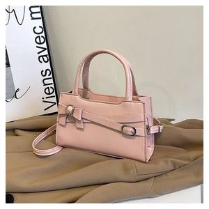 Detailed close-up of pink crossbody bag with leather texture and silver buckle bow decoration