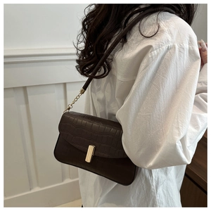 Detail view of a vintage dark brown crocodile embossed shoulder bag with gold metal clasp