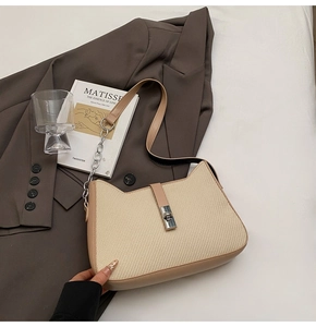 Close-up of beige woven texture handbag with silver metal clasp and leather strap trim