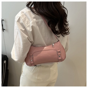 Close-up of pink glossy underarm bag featuring metallic buckle and rivets on model