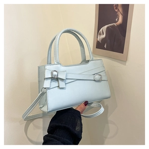 Detail of mint green PU leather handbag featuring a stylish bow and silver buckle