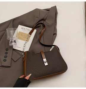 Detail of dark brown twill fabric shoulder bag with leather trim and silver buckle