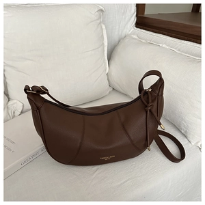 Close-up of dark brown lychee leather crescent bag with knot detail and gold logo
