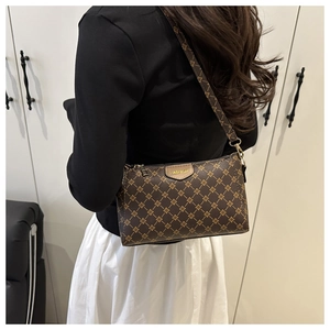 Detail of a brown crossbody bag with floral pattern and fashion metal plate on model