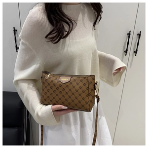 Close-up of brown floral pattern crossbody bag with leather FASHION patch and gold zipper