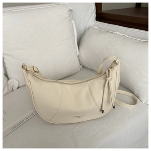 Detailed close-up of cream crescent bag featuring lychee grain leather and metal zipper