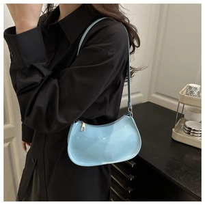 Light blue glossy patent leather baguette bag shown as a shoulder bag on a model