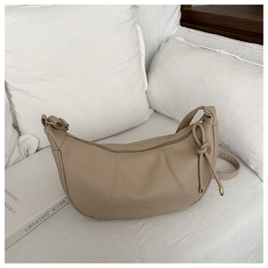 Detailed close-up of beige moon-shaped bag with litchi grain texture and knotted strap