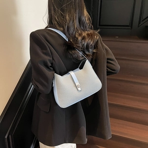 Light blue woven underarm bag with silver twist lock shown on model shoulder