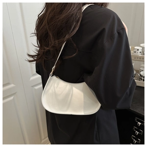 Detail of white patent leather shoulder bag with sleek curved design and gold hardware