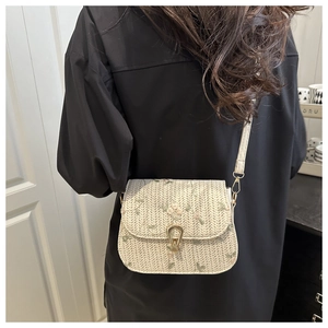 Detail of cream woven straw bag featuring floral embroidery and gold metal lock clasp