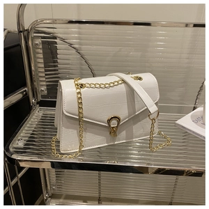 Close-up of white crocodile pattern shoulder bag with distinctive gold buckle and chain