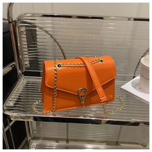 Detail of orange faux leather crossbody bag with crocodile texture and gold hardware