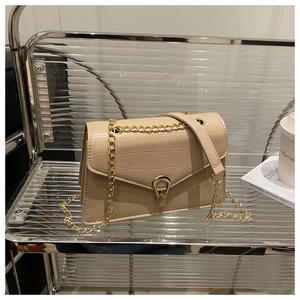 Detail of beige faux leather handbag with crocodile pattern and golden metal buckle