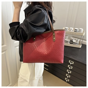 Detail of red woven tote bag featuring brown handles and gold rivet accents for commute