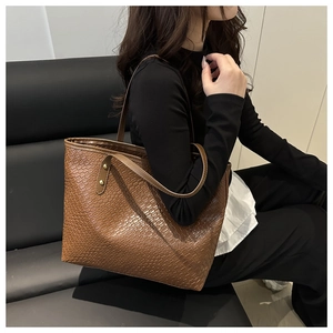 Close-up of brown woven tote bag showing fine texture and golden metal rivet details