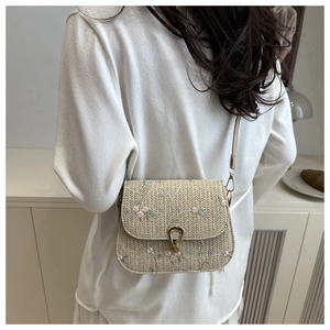 Detail of vintage woven mini crossbody bag featuring pink floral embroidery and gold buckle