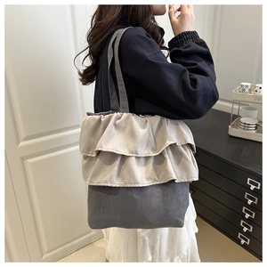 Close-up of double-layered ruffle details on a two-tone grey canvas tote bag