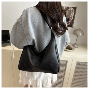 Detail view of large black leather tote bag with retro texture and wide shoulder strap