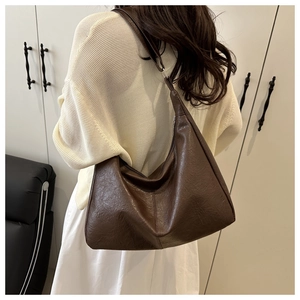 Detail view of a large brown leather hobo bag showing shoulder fit and retro texture