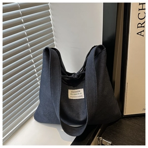 Detail of grey denim tote bag with FASHION label in a modern minimalist setting