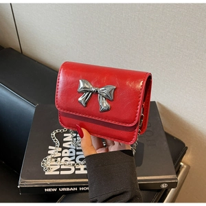 Detailed view of red PU leather small crossbody bag with silver metal bow and chain