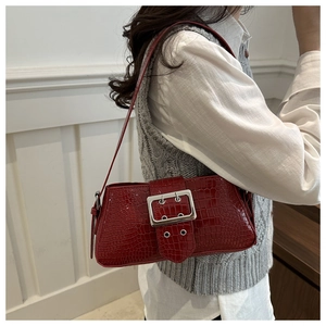 Detail of red croc-effect underarm bag with decorative large silver buckle on strap