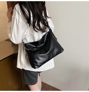 Detail view of large matte black tote bag with side metal chain and small coin purse