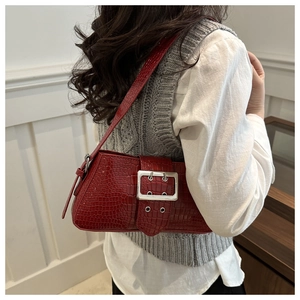 Close-up of red crocodile-embossed leather bag with a stylish silver metal buckle detail